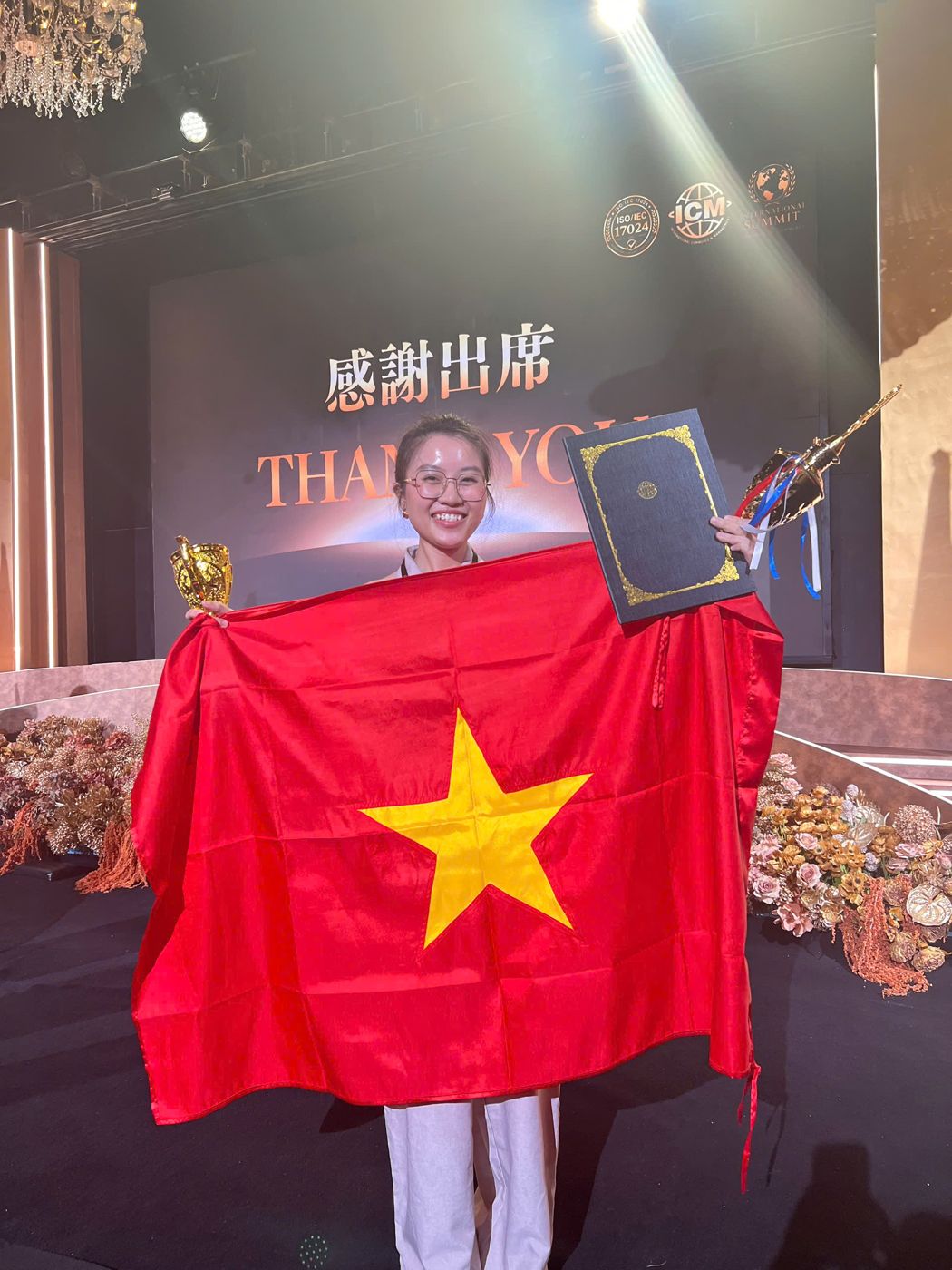 Chị Nguyễn Nhã Hy cầm lá cờ Việt Nam và cúp Á Quân trên sân khấu ISCC Global Beauty Championship 2026